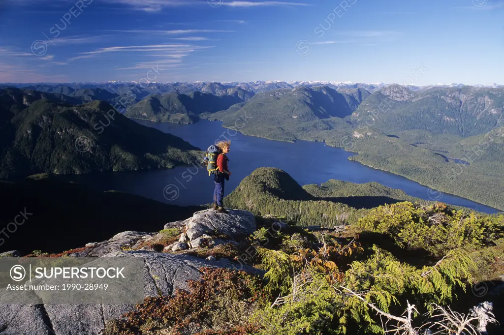 A woman stands above echo harbour, great bear rainforest, gilford island, British Columbia, Canada