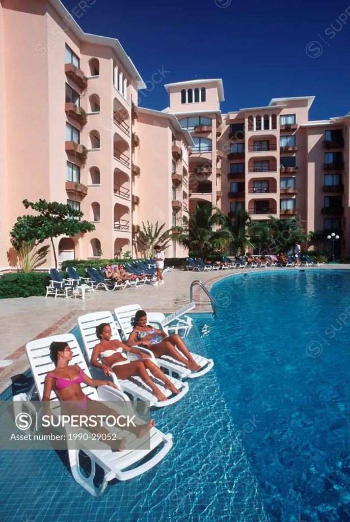 Mexico, Yucatan Peninsula, Carribean Resort at Cancun, three young women relax by swimming pool