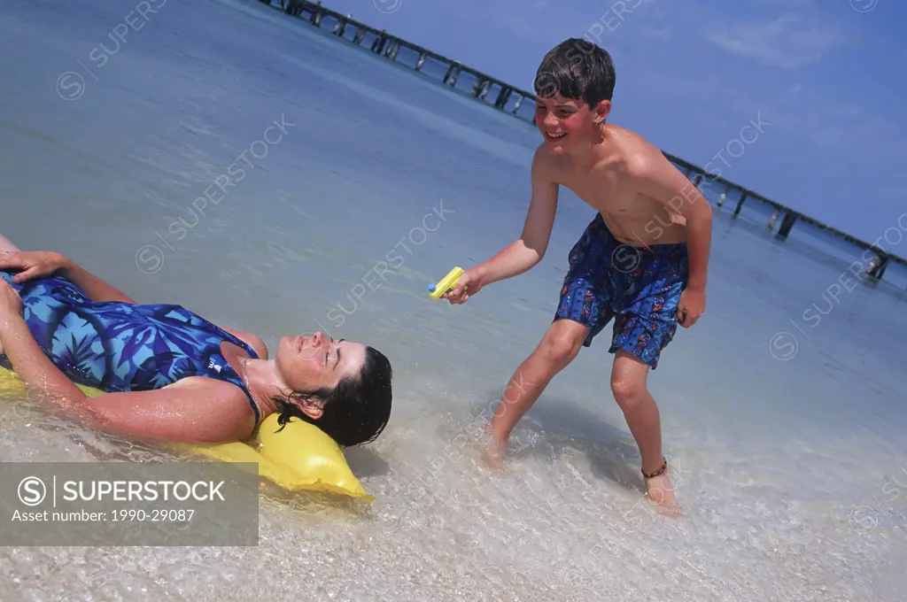 Mexico, Yucatan Peninsula, Carribean resort at Isla Mujeres, boy squirts water on mother on float mattress