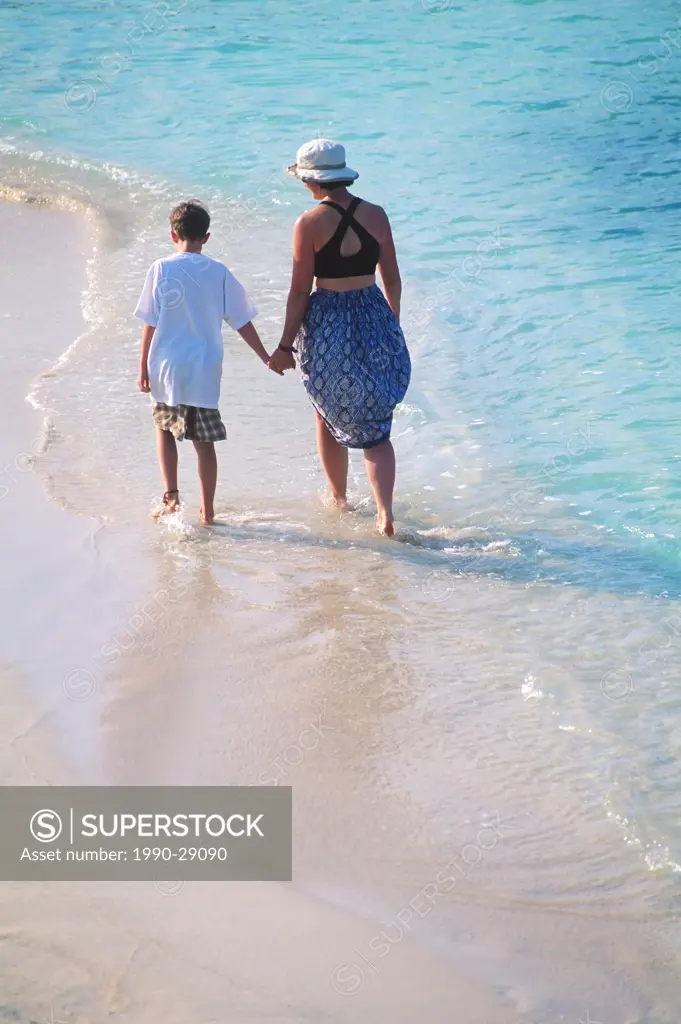 Mexico, Yucatan Peninsula, Carribean resort at Isla Mujeres, woman and son walk down beach