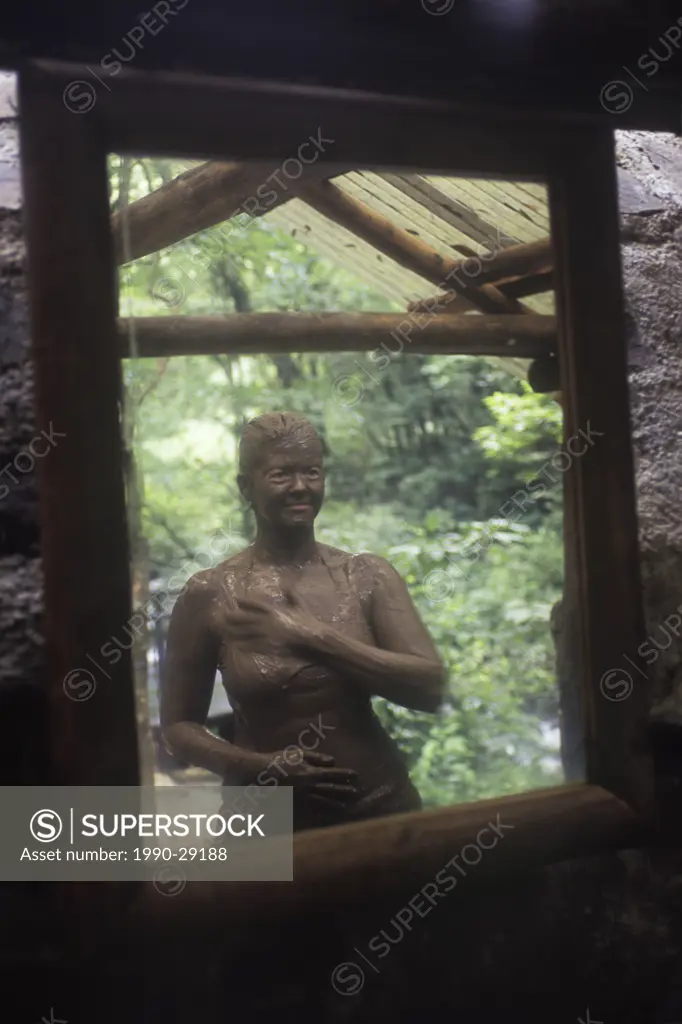 Costa Rica, Volcan Rincon de la Vieja area in Guancaste Province. Woman with volcanic mud at hot spring reflected in mirror.
