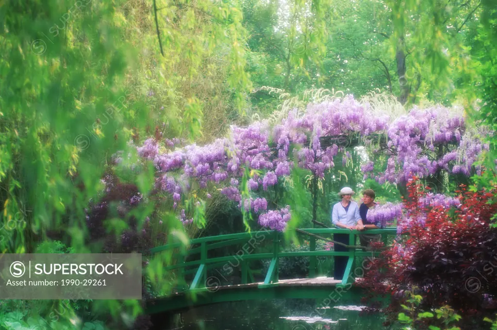 France, Giverney _ Monet´s Garden _ Diffuse woman on bridge with wisteria in full bloom