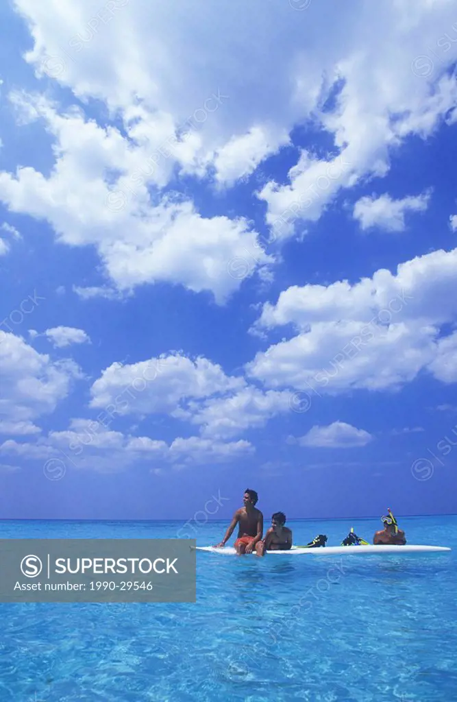 Cuba, Veradaro, local boys on wind surf board, cumulus cloud over azure water of carribean sea