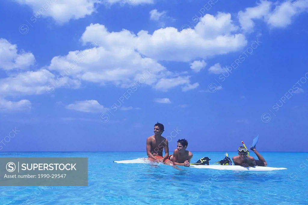 Cuba, Veradaro, local boys on wind surf board, cumulus cloud over azure water of carribean sea