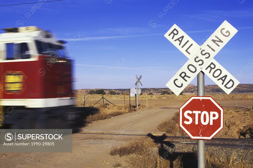 Freight train with motion blur at level crossing with railway sign
