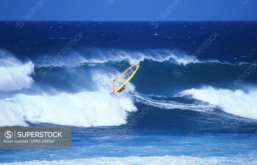 USA, Maui _ Male windsurfing in large surf waves.