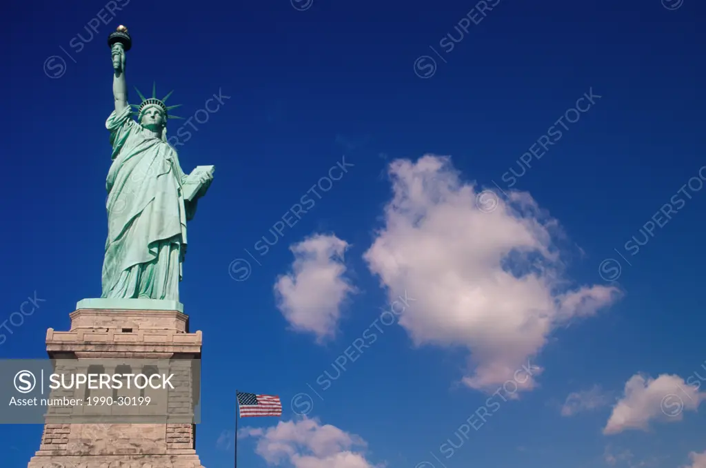 USA, New York City, Statue of Liberty with cumulus clouds and US Flag