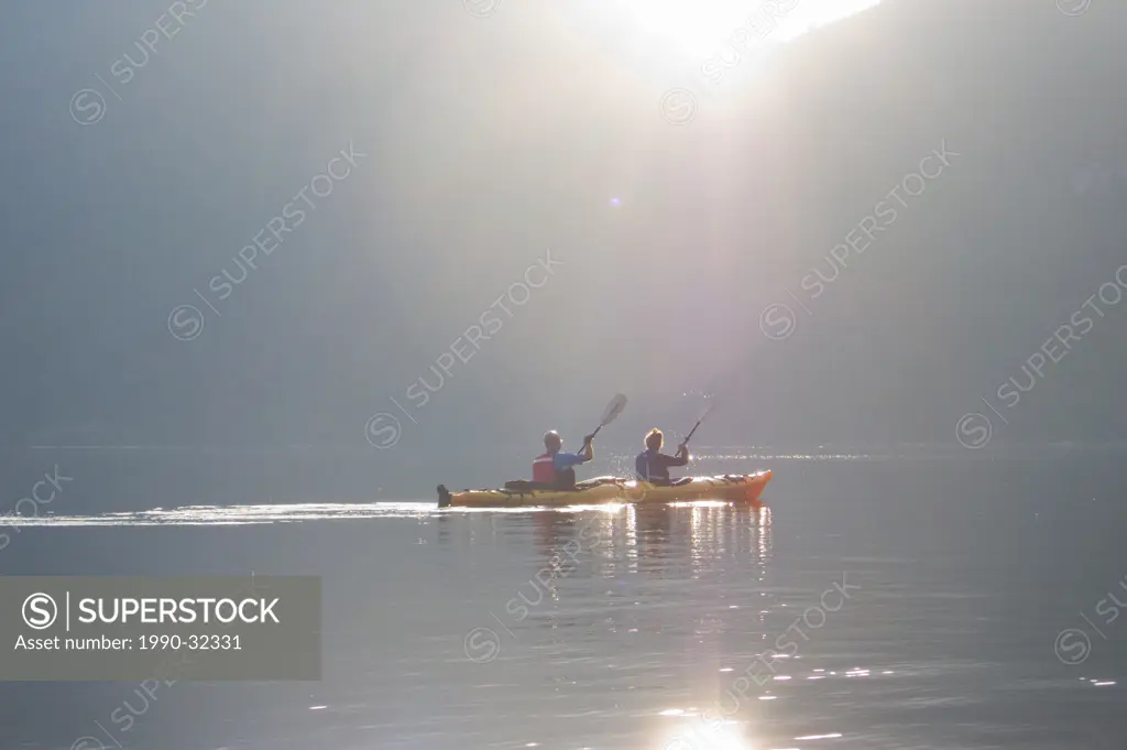 Kayakers paddling towards Harmony Islands in Hotham Sound at sunset along the British Columbia coast Canada