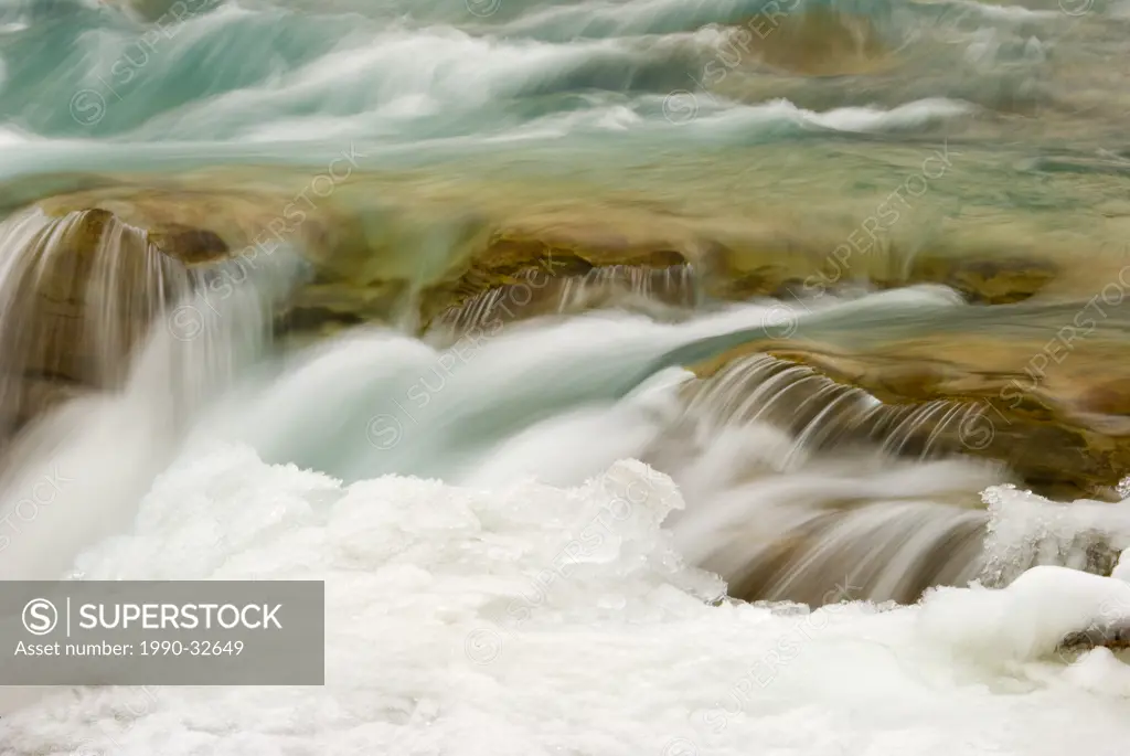 Flowing snowy river water before it plunges over the majestic Athabasca Falls in the Rocky Mountains near Jasper, Alberta, Canada.