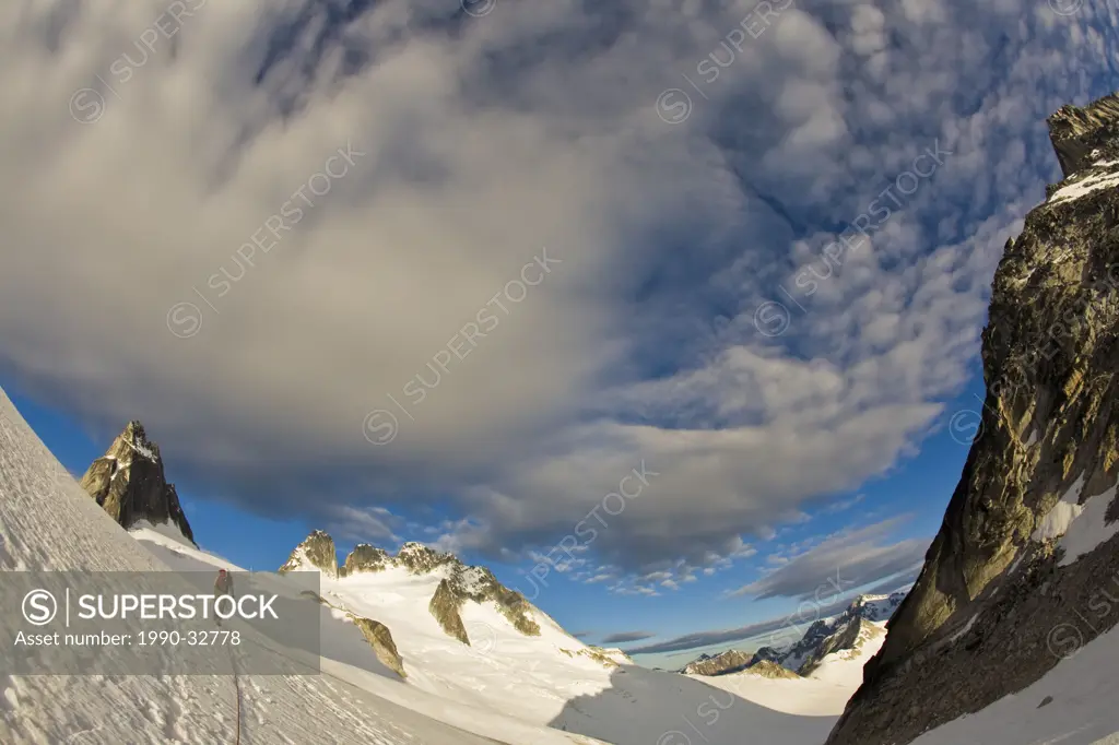 A female climber ascends toward the Northeast Ridge _ North Howser, Bugaboos, BC