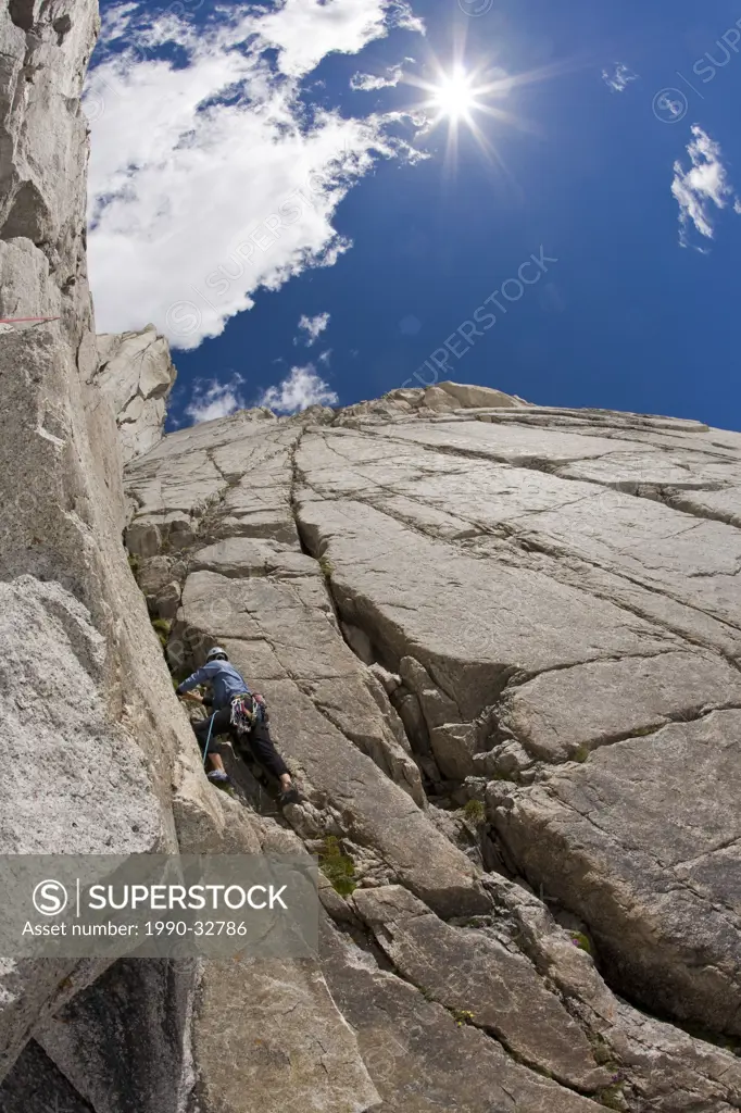 A female climber prepares to rockclimb Paddle Flake 5.10 Bugaboos, BC