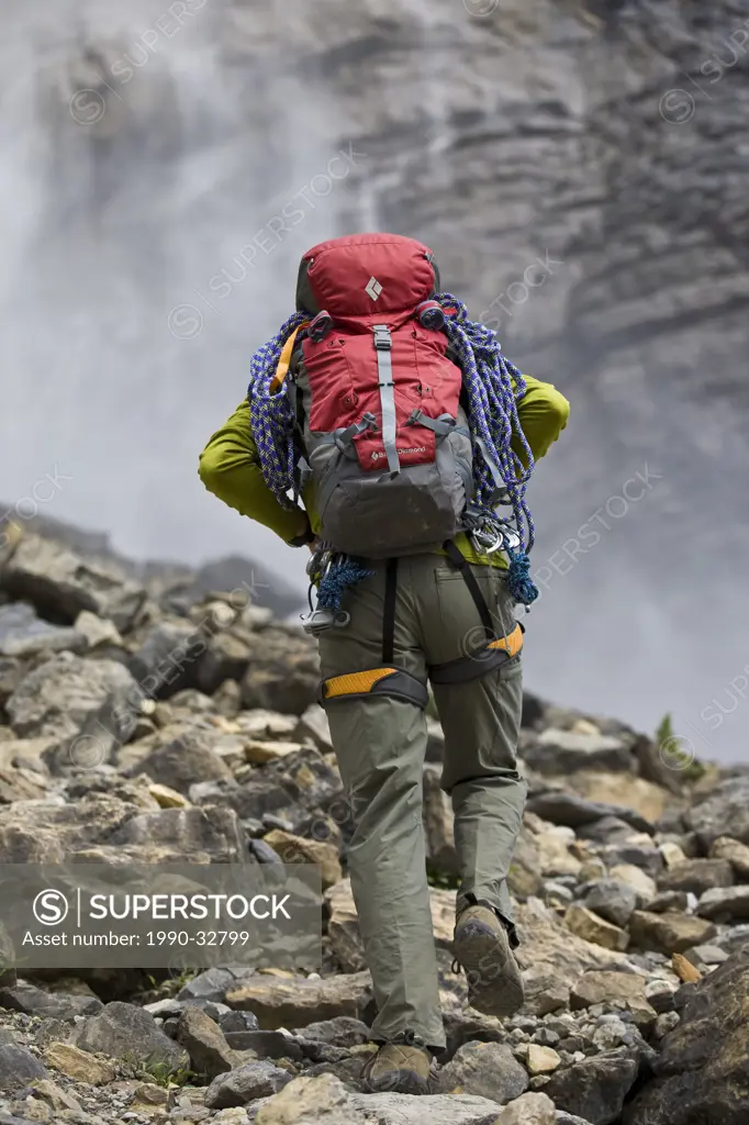 A young man hikes into Takakkaw Falls, Yoho National Park, BC