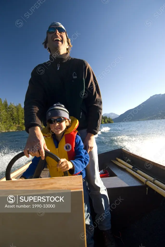 A father and son enjoy a speed boat trip in their home_made boat on Tatlayoko Lake, British Columbia, Canada