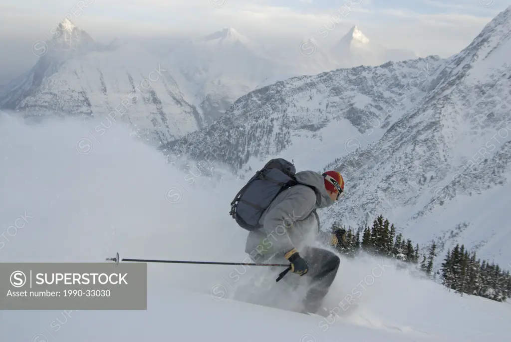 A male skier streaks down the slopes of Rogers Pass in front of MacDonald Peak and Mount Sir Donald, Selkirk Mountains, British Columbia