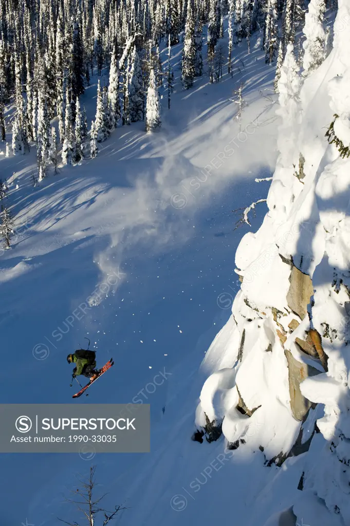 A male skier takes a huge jump off a cliff in the Whitewater Winter Resort backcountry, British Columbia