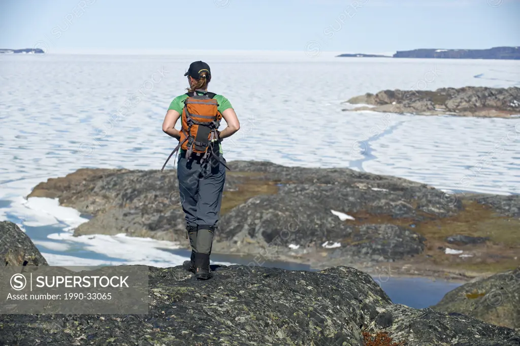 A woman hiking on the shores of the frozen Arctic Ocean, Nunavut
