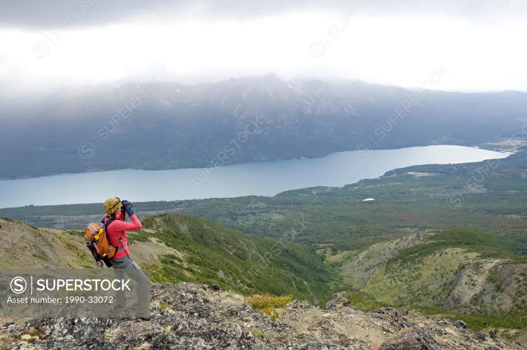 A woman surveys over Tatlayoko Lake with binoculars, British Columbia Coast Mountains