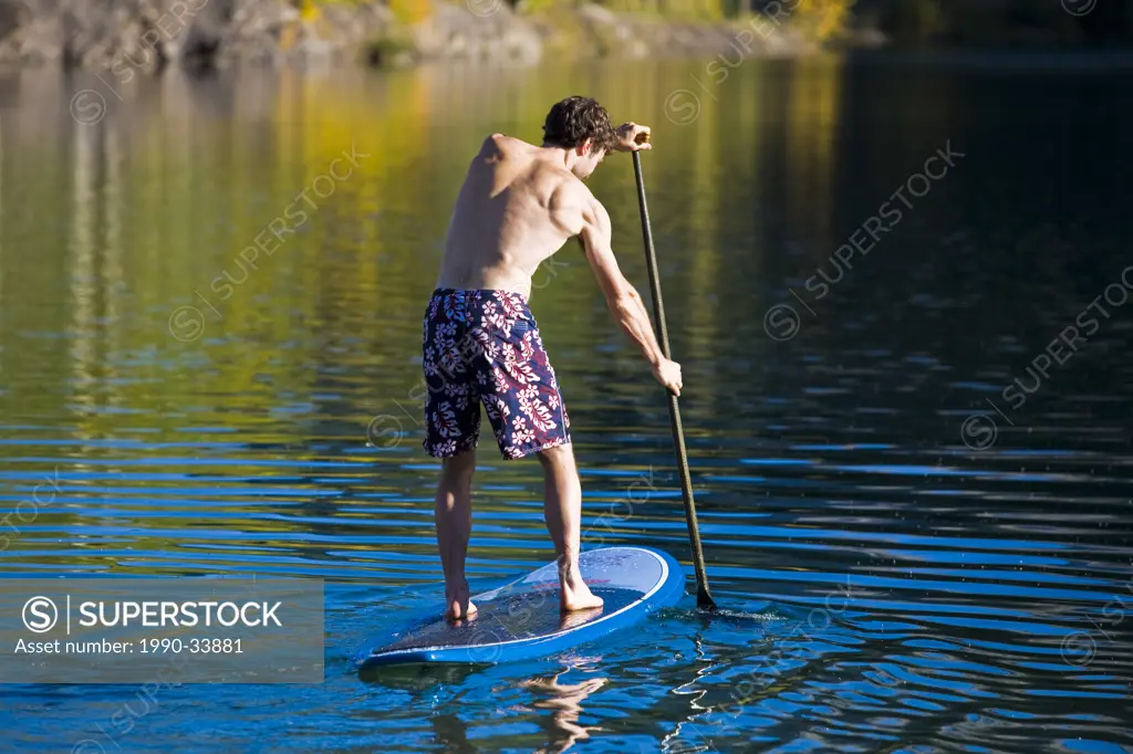 A young man paddleboards on Quarry lake in Canmore, AB