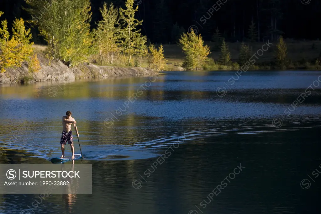 A young man paddleboards on Quarry lake in Canmore, AB