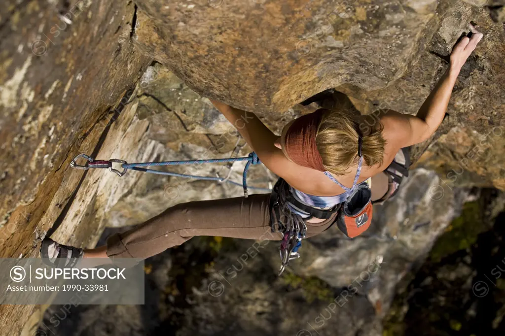 A young woman sport climbs Rechargeable Battery 5.11d, Mt. Orford, QC