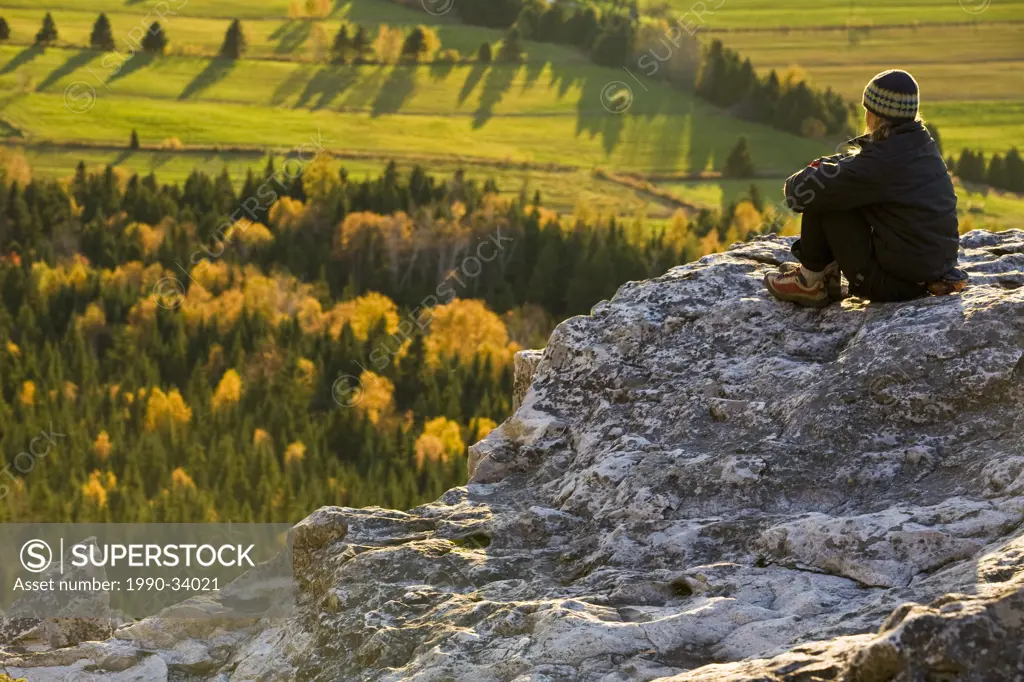 A young woman enjoying the view while rockclimbing in Kamouraska, QC
