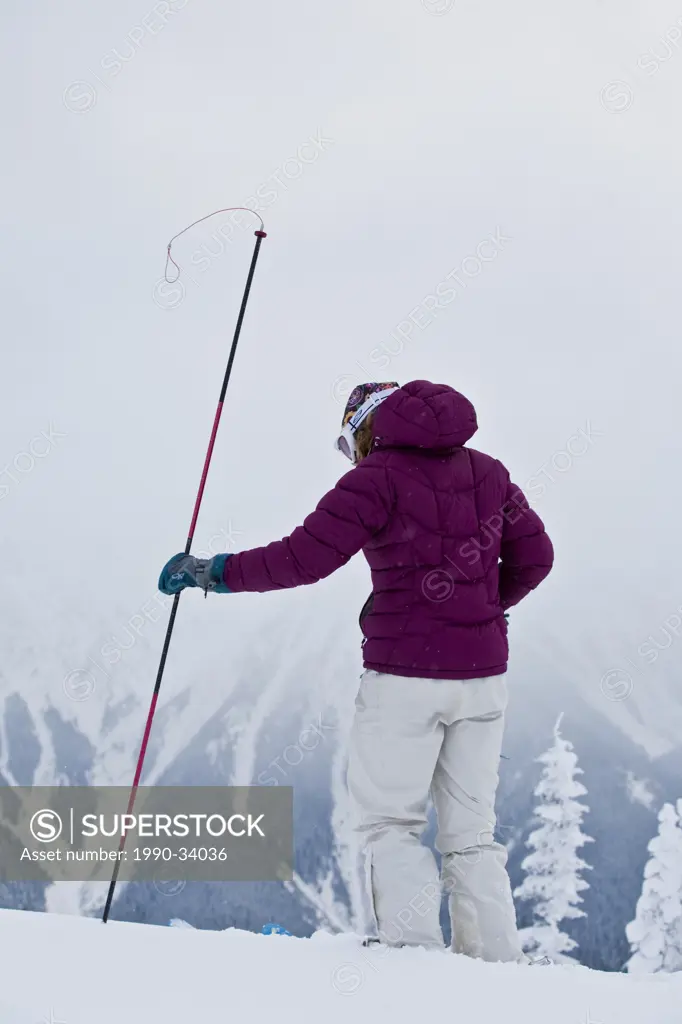 A young woman probing the snowpack in the Revelstoke Backcountry, BC