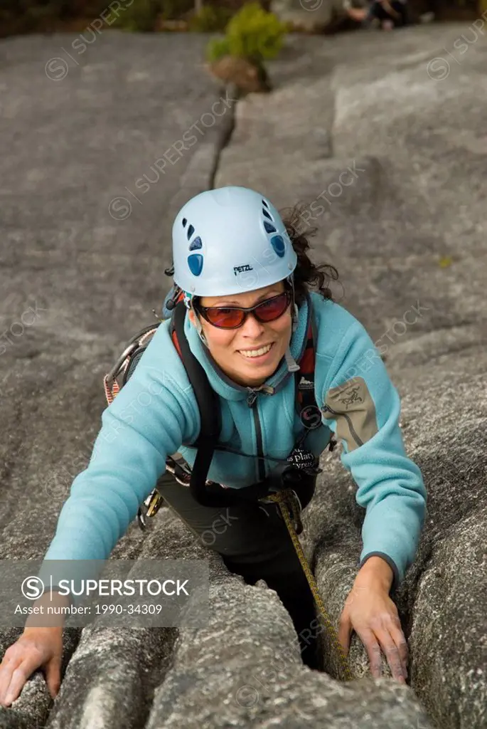 A young woman climbs up St. Vidas´ Dance on the Apron, Squamish, British Columbia, Canada