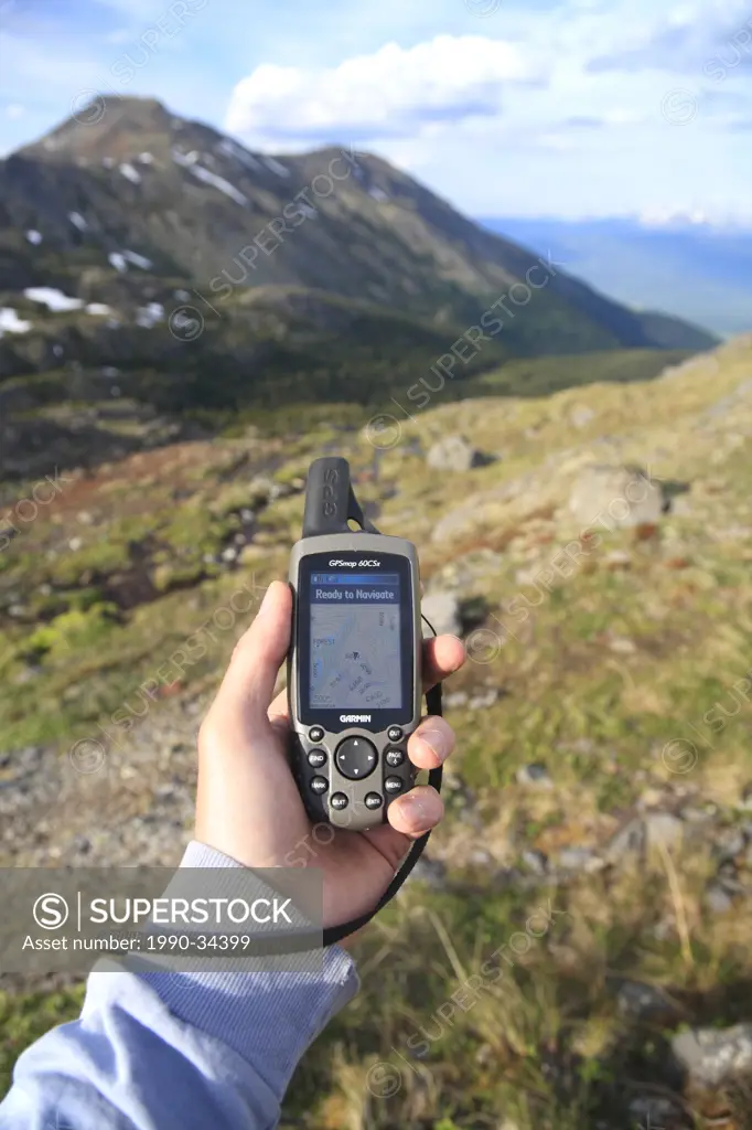 Hiker holding GPS unit in alpine, Hudson Bay Mountain, Smithers, British Columbia