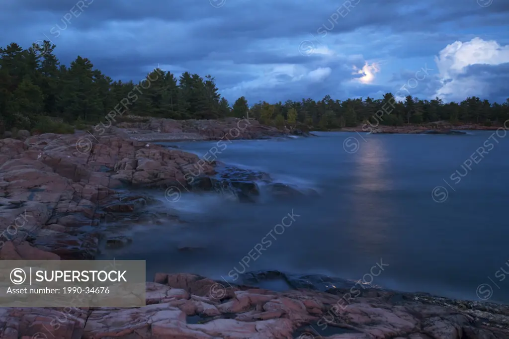 A full moon is unveiled as clouds pass over Georgian Bay in Killarney Provincial Park in Northern Ontario.