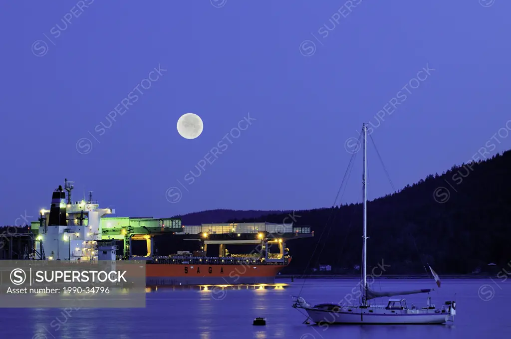 A freighter and sailboat under full moon in Cowichan Bay, British Columbia, Canada