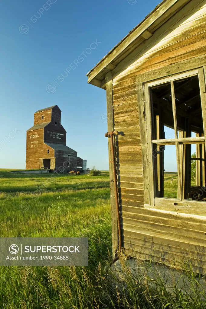 old house with grain elevator in the background, abandoned town of Bents, Saskatchewan, Canada