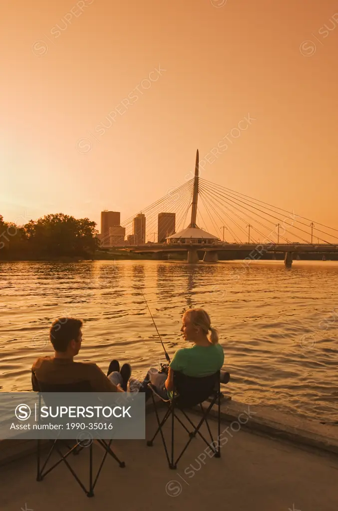 couple relaxing on dock along the Red River, Winnipeg skyline from St. Boniface, Manitoba, Canada