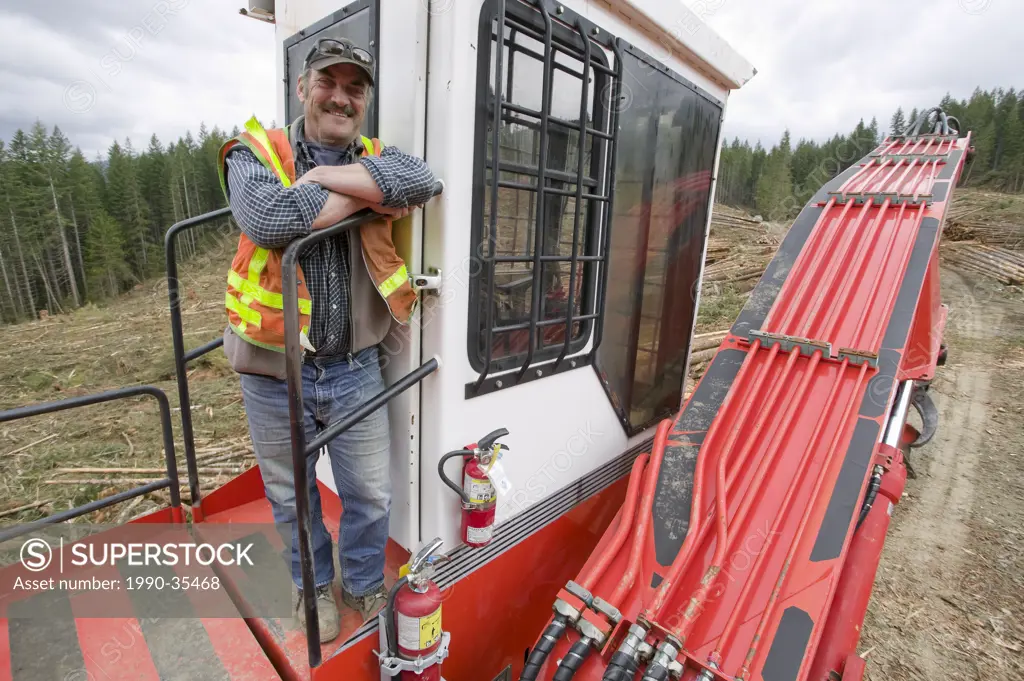 An operator atop his grapple loader or ´Hoe_Chucker´, Sayward, Cambell RIver, Vancouver Island, British Columbia, Canada.