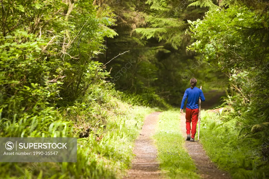 A young hiker strolls along a path, Ronning Garden, Holberg, Northern Vancouver Island, British Columbia, Canada.