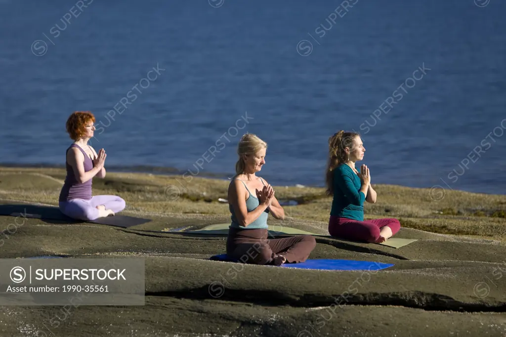 Yoga practioners on Denman Island meditate and relax in the lotus position. Denman Island, The Comox Valley, Vancouver Island, British Columbia, Canad...