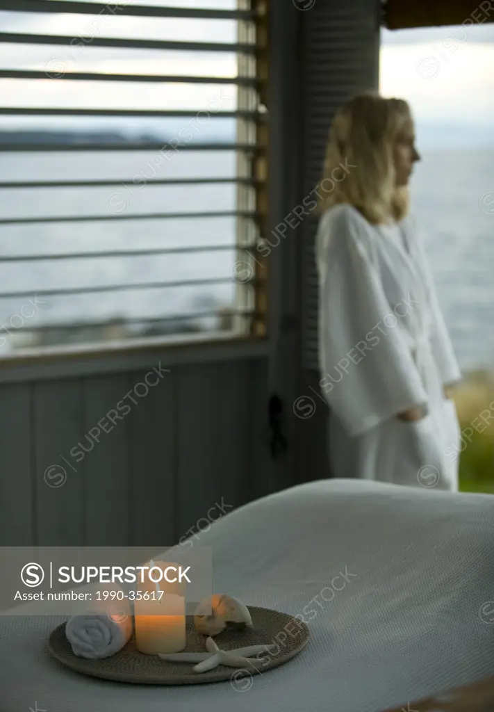 A young woman gazes out ot the Ocean in front of a beach front massage hut. Courtenay, The Comox Valley, Vancouver Island, British Columbia, Canada.