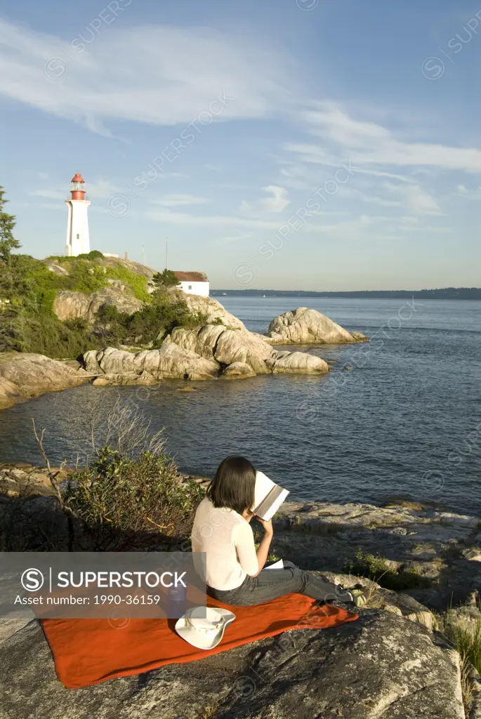 Woman relaxing with book at Lighhouse aprk, West Vancouver, BC, Canada