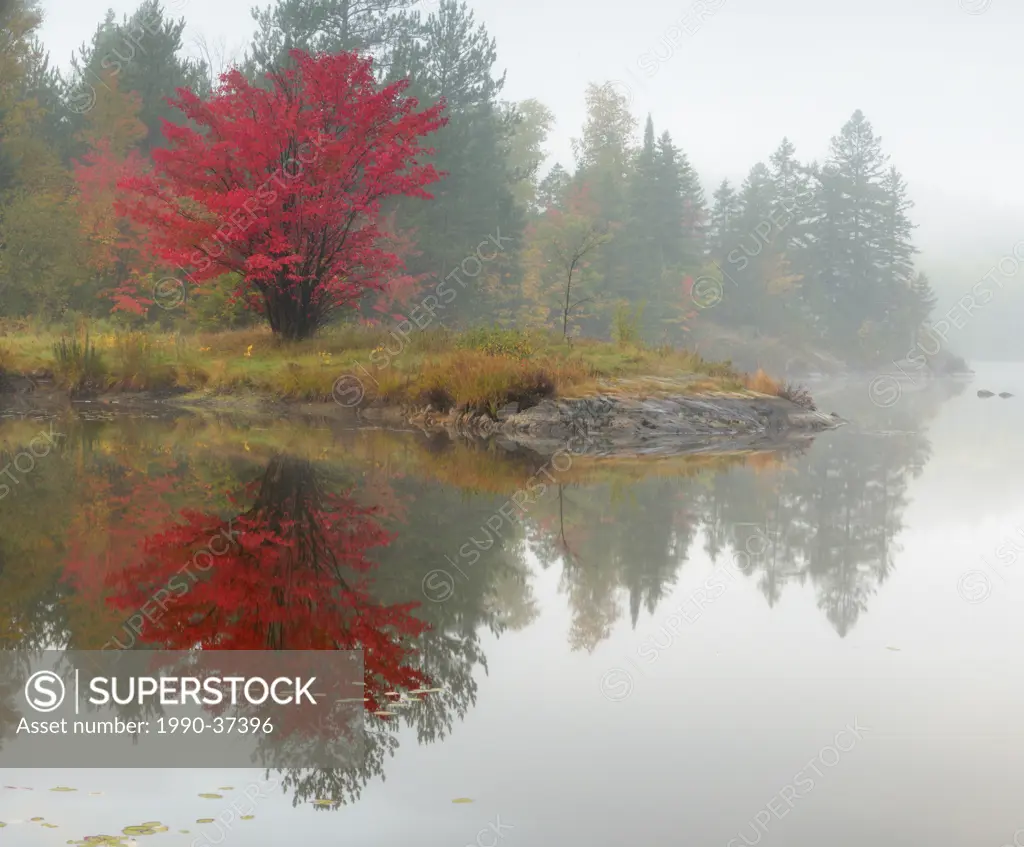 Autumn reflections in Bass Lake with light fog. Greater Sudbury, Ontario, Canada.