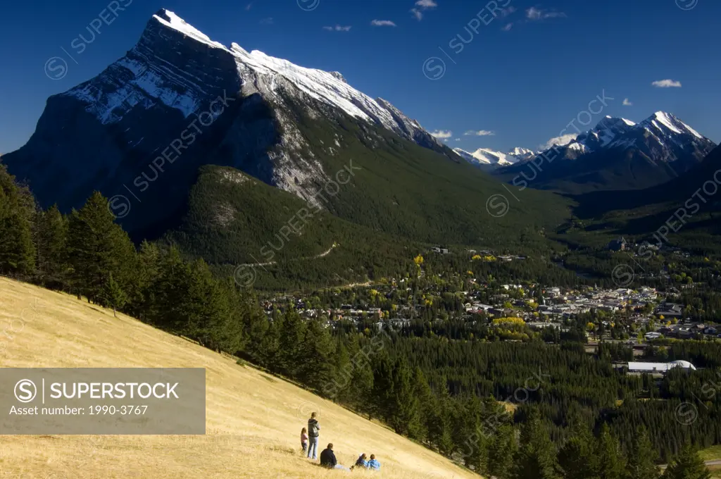 Visitors in meadow overlooking Banff townsite from Mount Norquay, Alberta, Canada