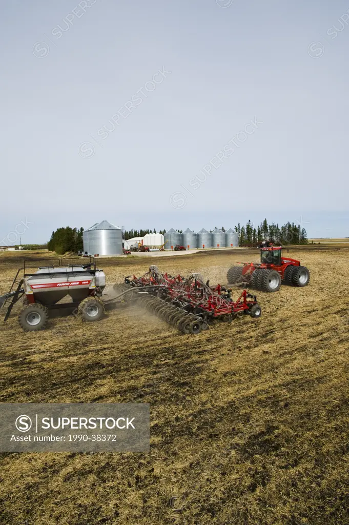 moving tractor and and air till seeder planting canola in grain stubble, near Dugald, Manitoba, Canada