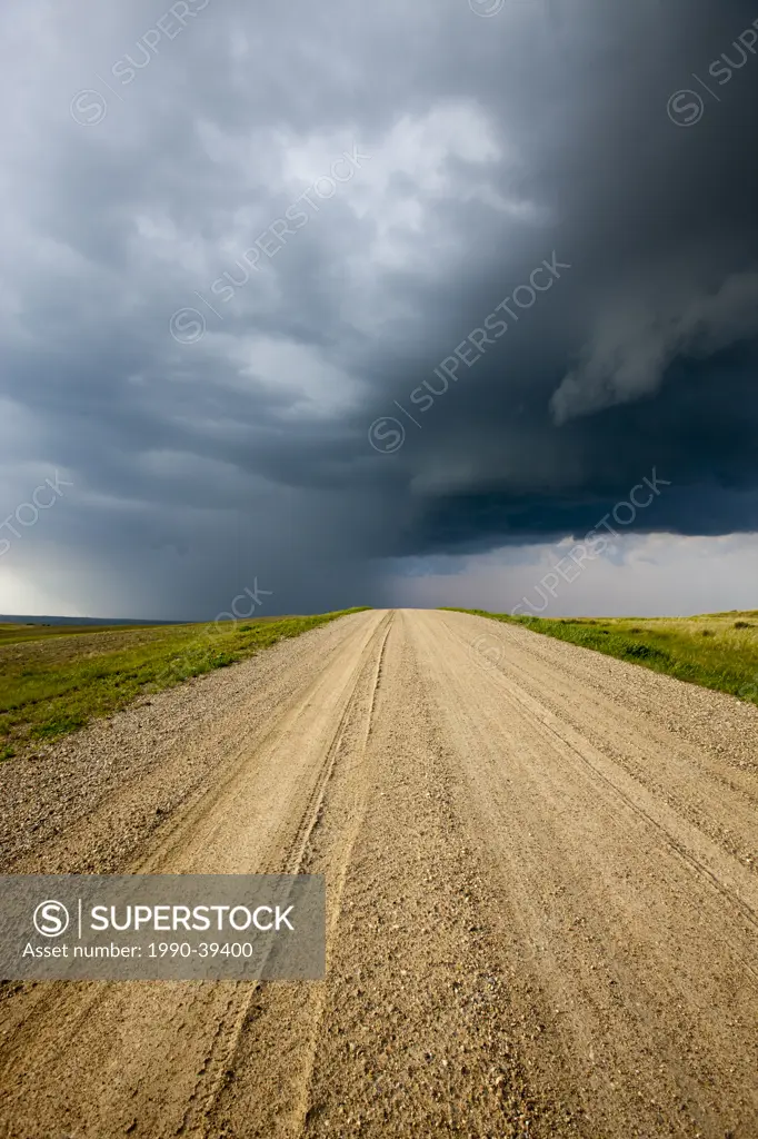 Storm clouds over a dirt road through the prairies, Saskatchewan, Canada.
