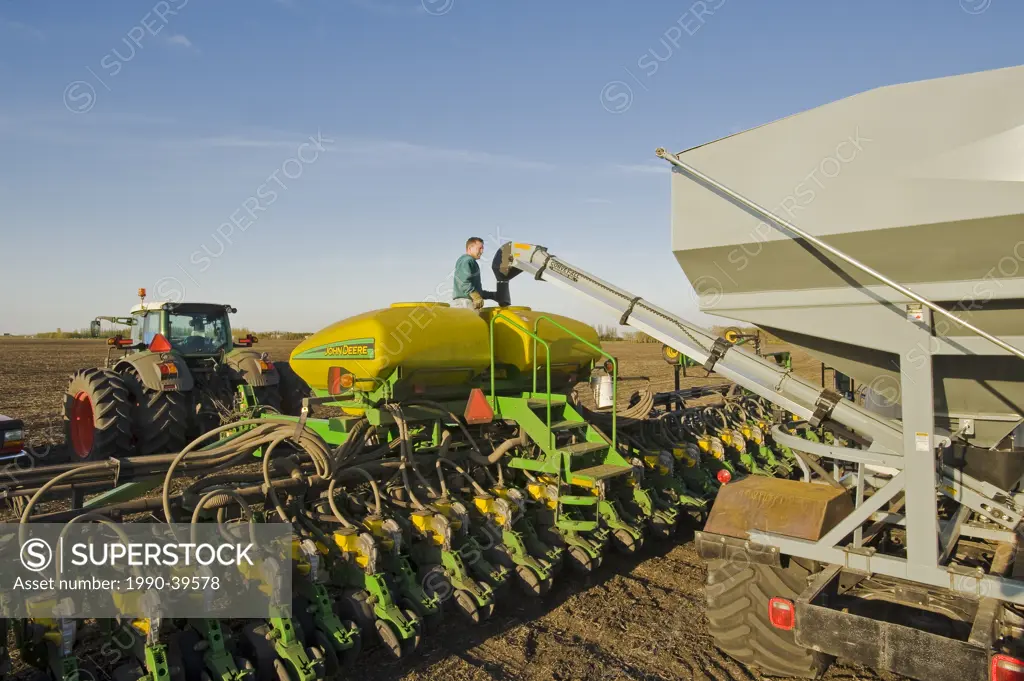 a farmer loads a seeder tank with soybean seed, near Lorette, Manitoba, Canada