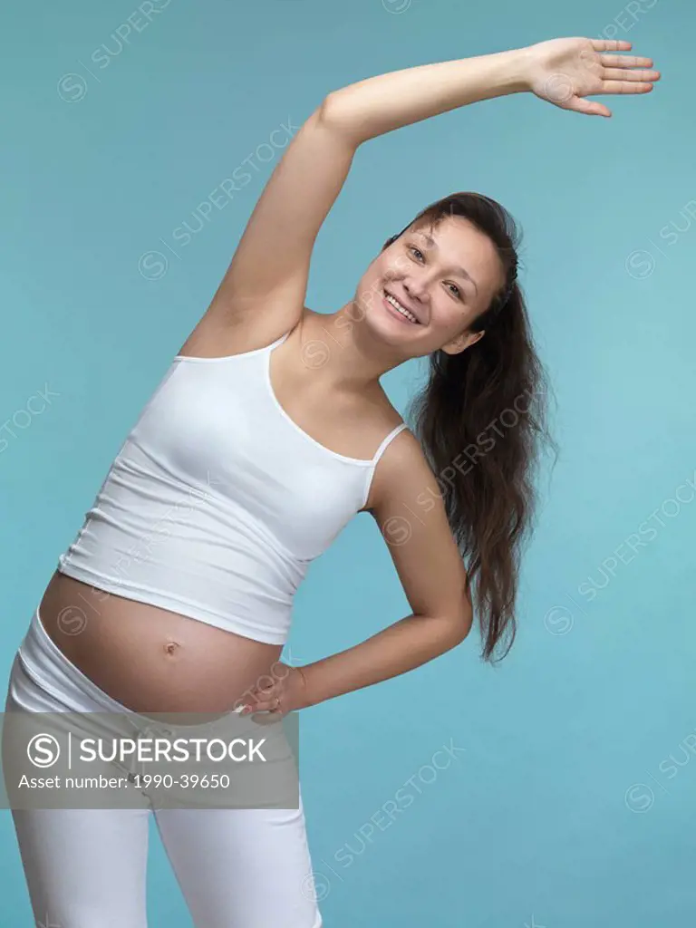 Smiling young pregnant woman exercising. Seventh month of pregnancy.