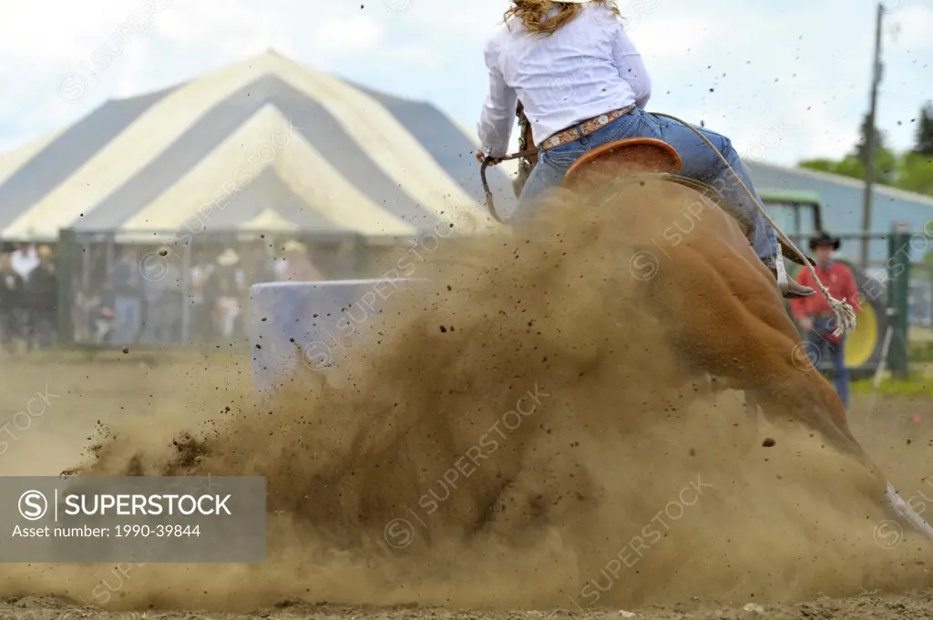 A rodeo rider competing in a barrel racing event under dusty arena conditions.