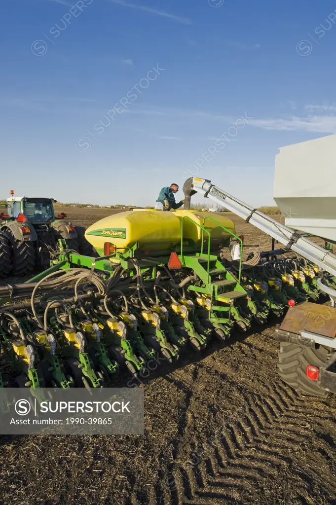 a farmer loads a seeder tank with soybean seed near Lorette, Manitoba, Canada