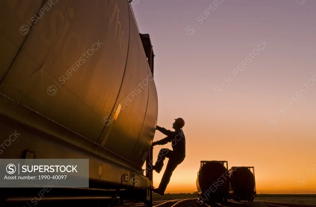 a worker climbs a grain rail hopper car at an inland grain terminal, Manitoba, Canada