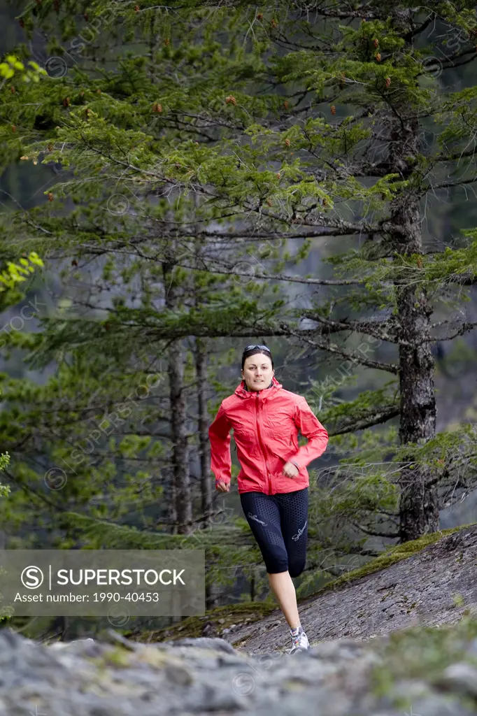 Woman trail running through a forest in the Squamish_Whistler region, British Columbia, Canada.