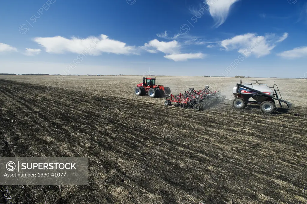 moving tractor and and air till seeder planting wheat, near Dugald, Manitoba, Canada