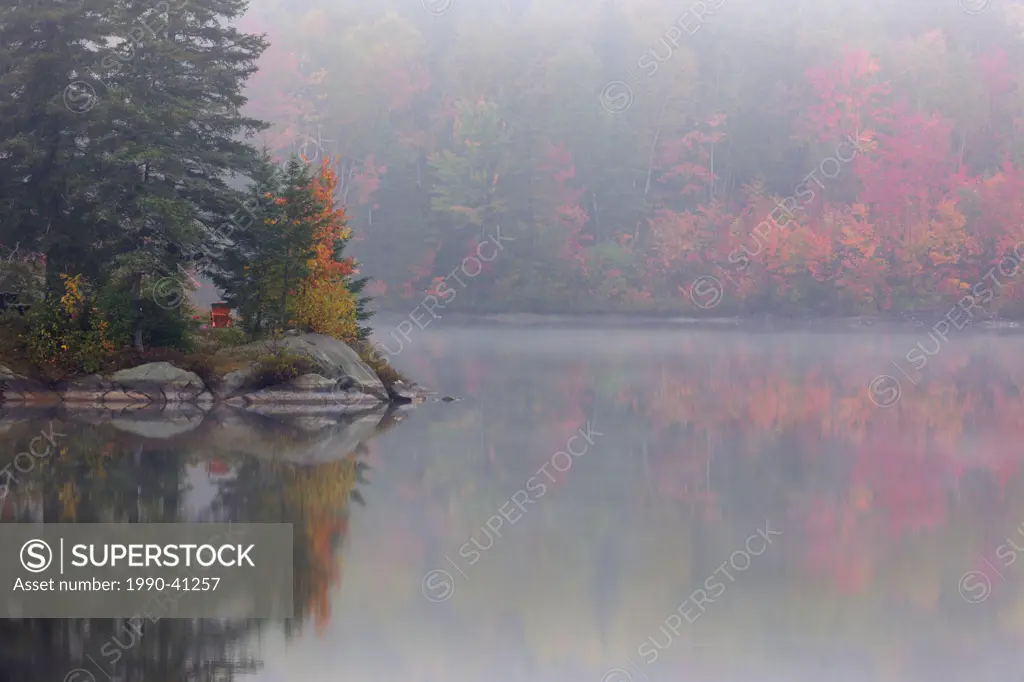 Autumn reflections in Bass Lake on a foggy morning. Greater Sudbury, Ontario