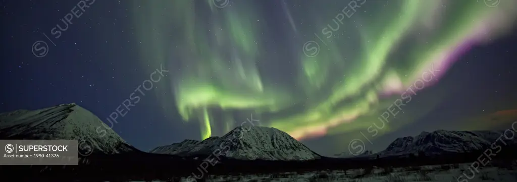 Dramatic aurora borealis display over mountains outside of Annie Lake, Yukon.